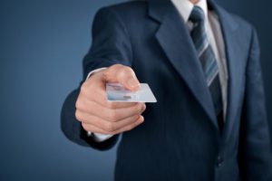 בתמונה - אדם לבוש חליפת עסקים מושיט ידו עם כרטיס אשראי